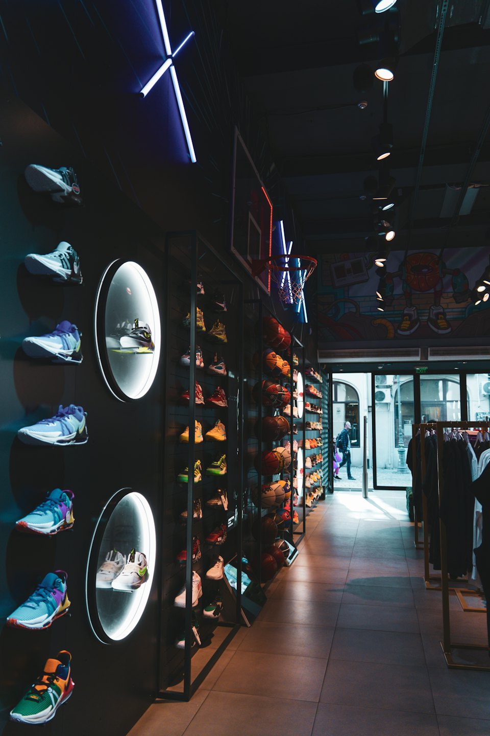 Zapatillas deportivas expuestas en expositores y estanterías de una tienda moderna.
